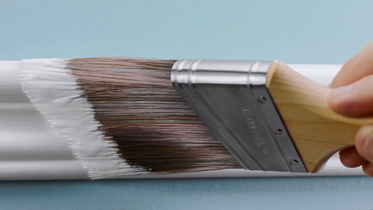 Paint brush with white paint, white moulding, pale blue wall